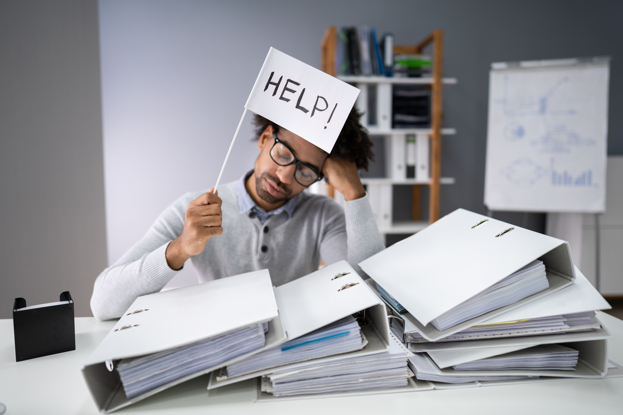 Overwhelmed business man with documents as the featured image of "How Do You Know Which Documents Need to Be Shredded?"